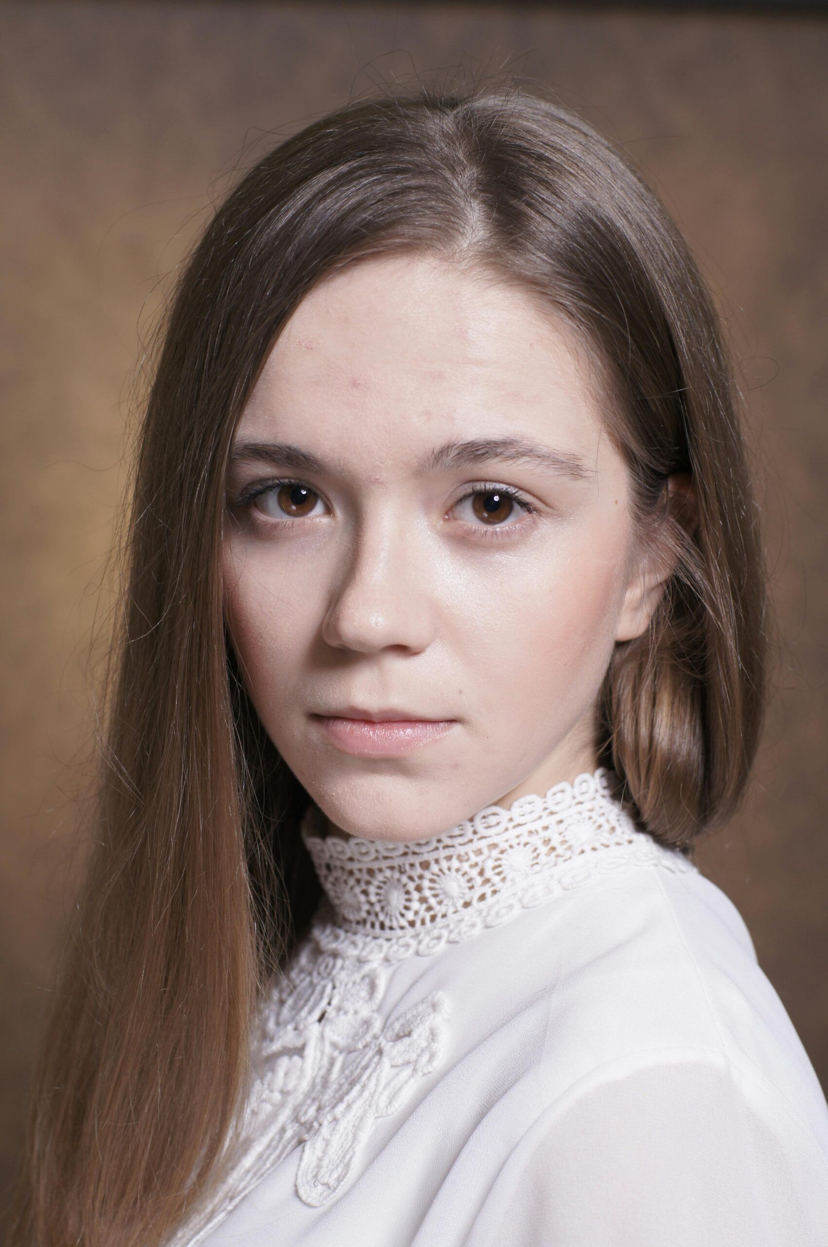 Elegant portrait of a young woman with long hair and lace collar, expressing calmness.